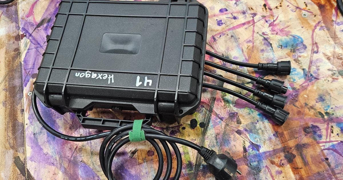 A finished waterproof pixel controller - black hard case with four xConnect pigtails and a power lead, on a paint-spattered workbench.